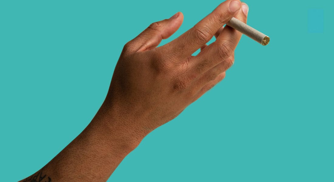 Hand holding straight-rolled cannabis joint