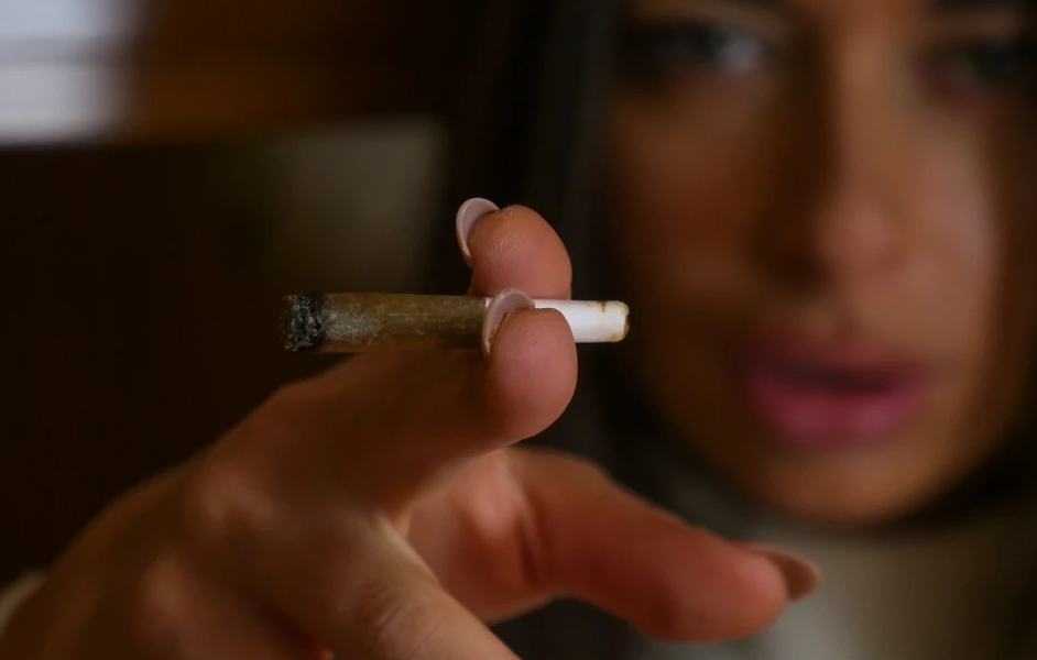 Woman Pointing at the Camera with a Smoke in Hand