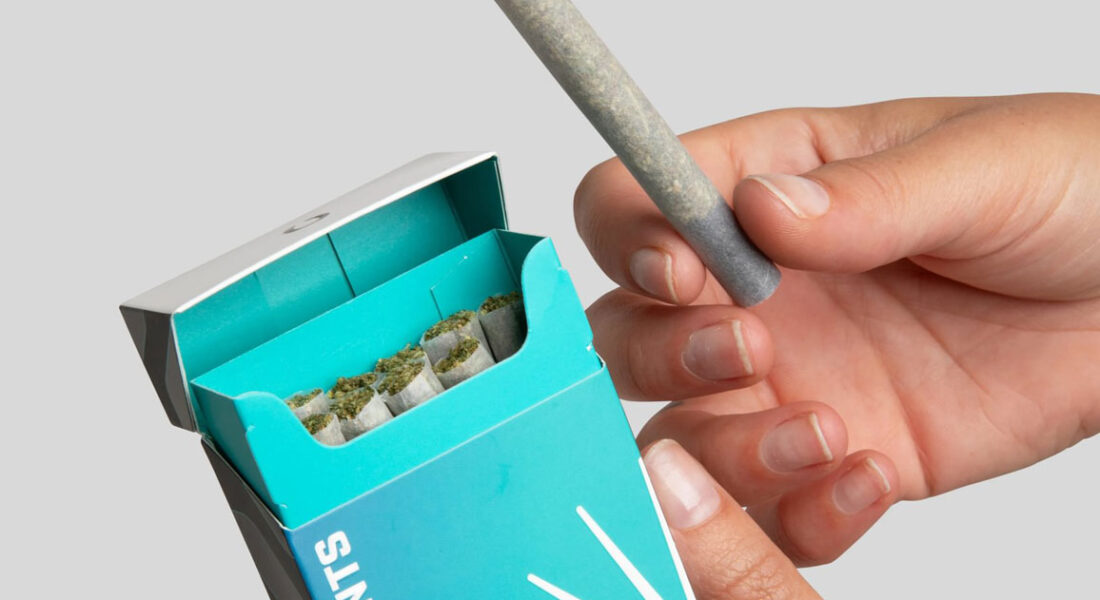hands holding a rolled joint from a box of pre-rolls