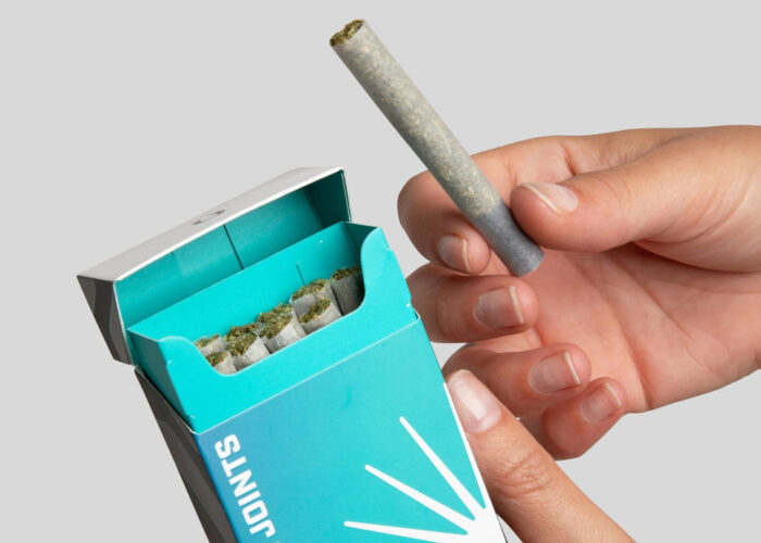hands holding a rolled joint from a box of pre-rolls