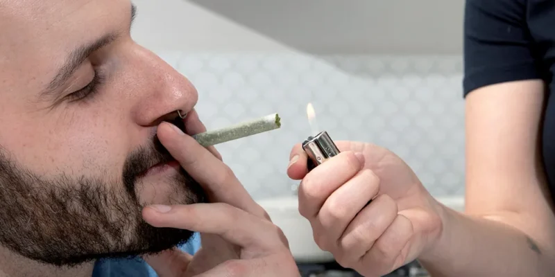 ROLL-DogHouse-smoking-1 person lighting a joint