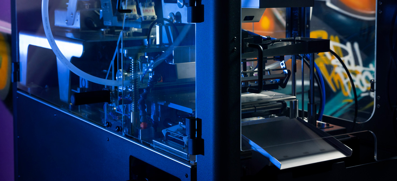 The Role of Automation in Modern Production Gemini said A detailed look at the inner mechanics of an automated pre-roll machine under blue light, featuring a metal slide and graffiti-style branding.