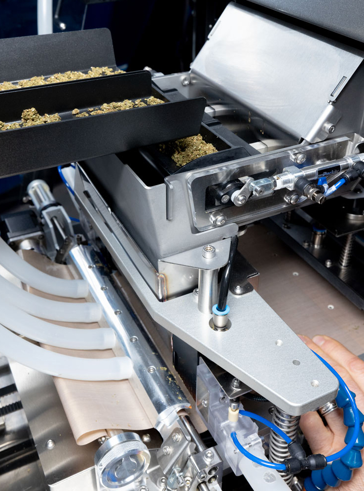 The Role of Automation in Modern Production Automated cannabis grinding and weighing system dispensing ground flower into a pre-roll production machine.