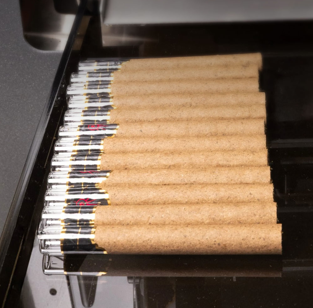 The Role of Automation in Modern Production A row of professionally rolled blunts with glass tips neatly arranged on a production tray for packaging.